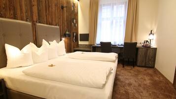 A hotel room with a large bed, a desk, and a chair.
