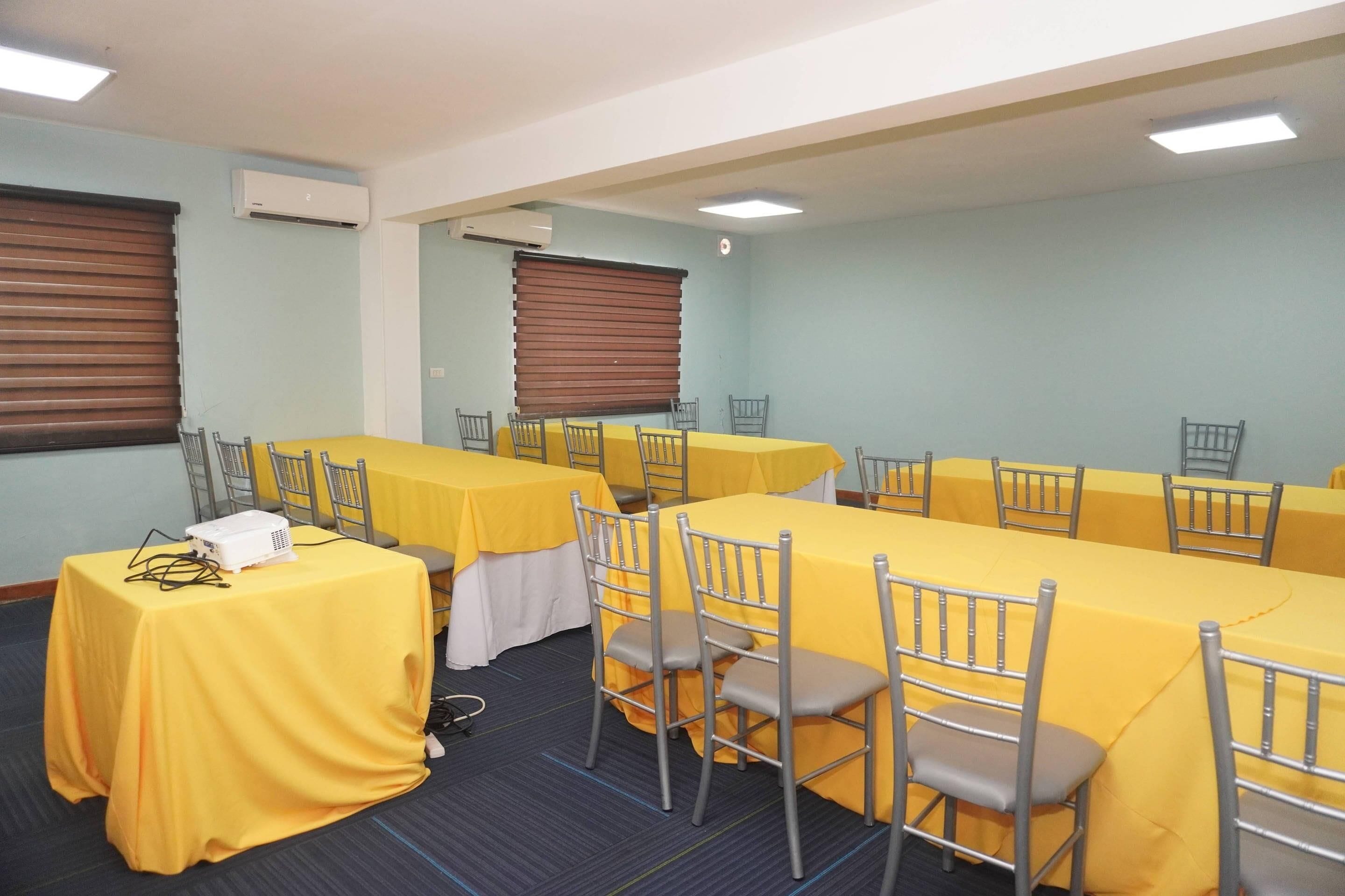 A conference room with tables and chairs, air conditioning units, and a projector.