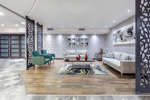 Un salon moderne comprenant un canapé, deux fauteuils, une table basse et des vases décoratifs.