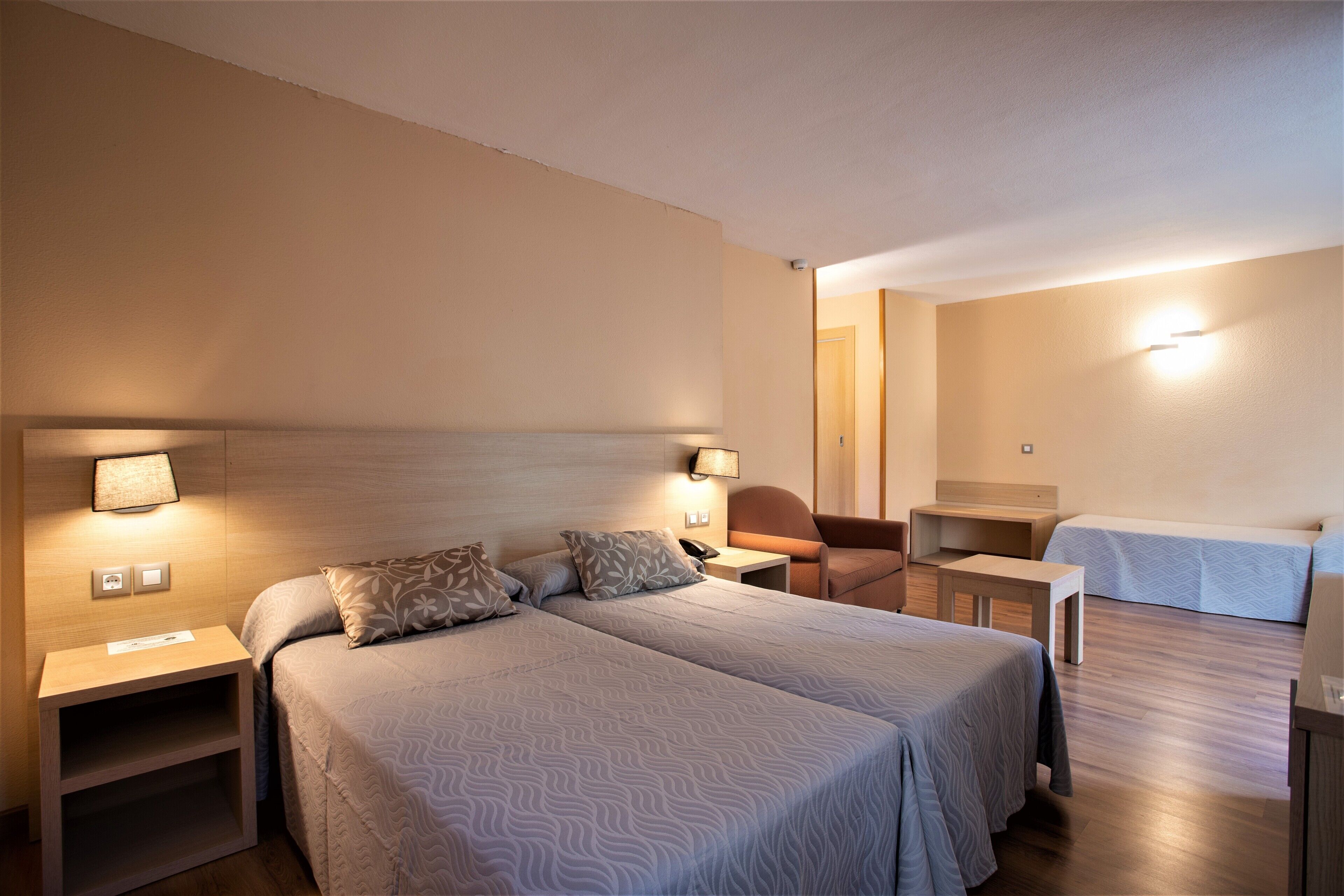 Una habitación de hotel con dos camas, un escritorio, una silla y una mesita.