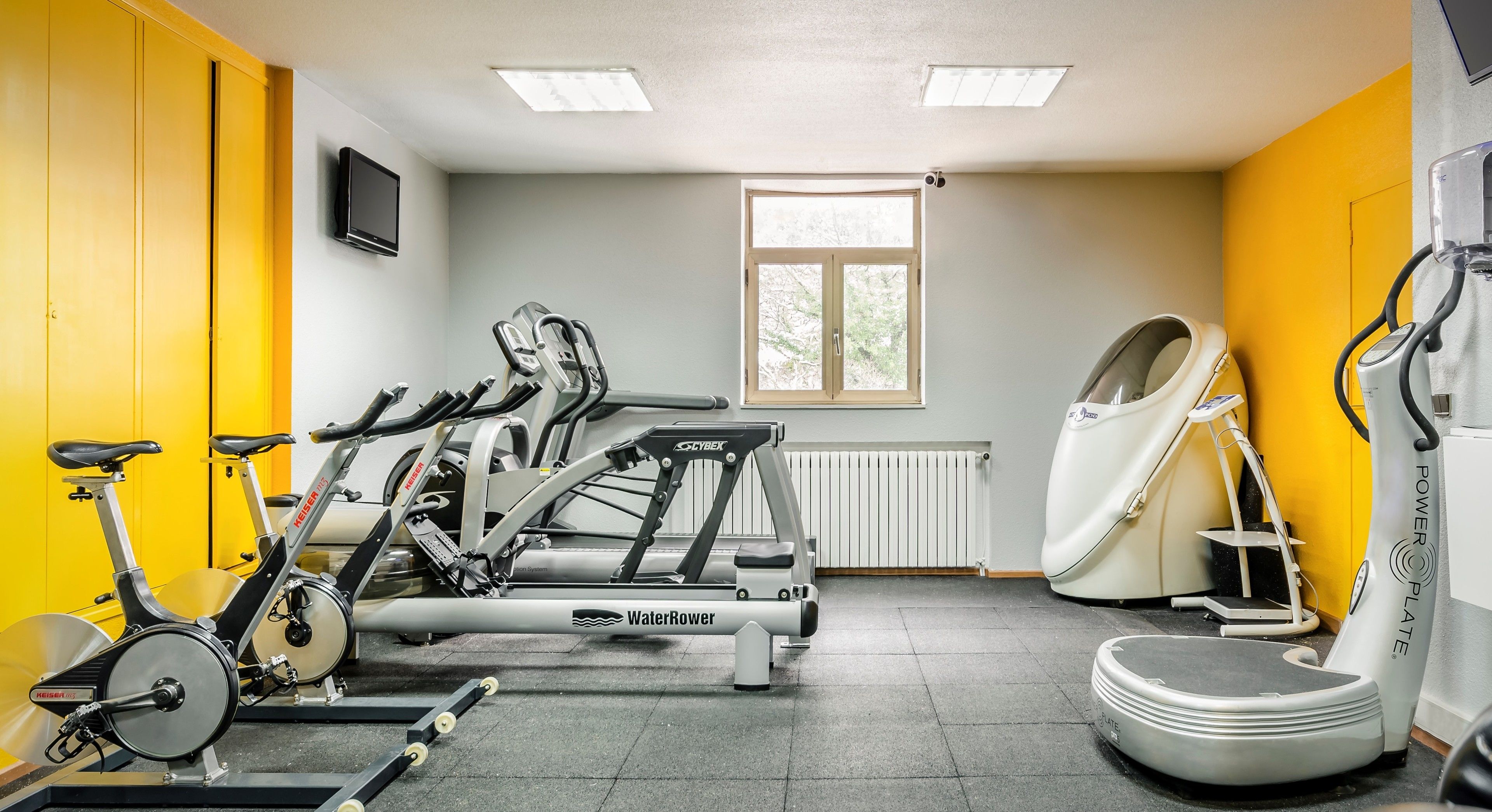 Un gimnasio con bicicletas estáticas, una cinta de correr y una máquina de remo.