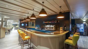 Un área de bar con mostrador, taburetes y una máquina de café.