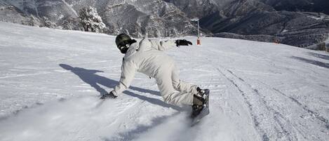 A snowboarder on a snowy slope with mountains in the background.