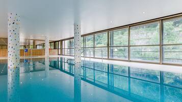 Een binnenzwembad, ligstoelen bij het zwembad