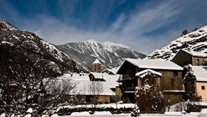 Un pueblo cubierto de nieve con edificios tradicionales, una iglesia y montañas al fondo.