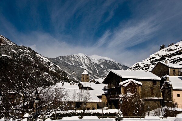 Un pueblo cubierto de nieve con edificios tradicionales, una iglesia y montañas al fondo.