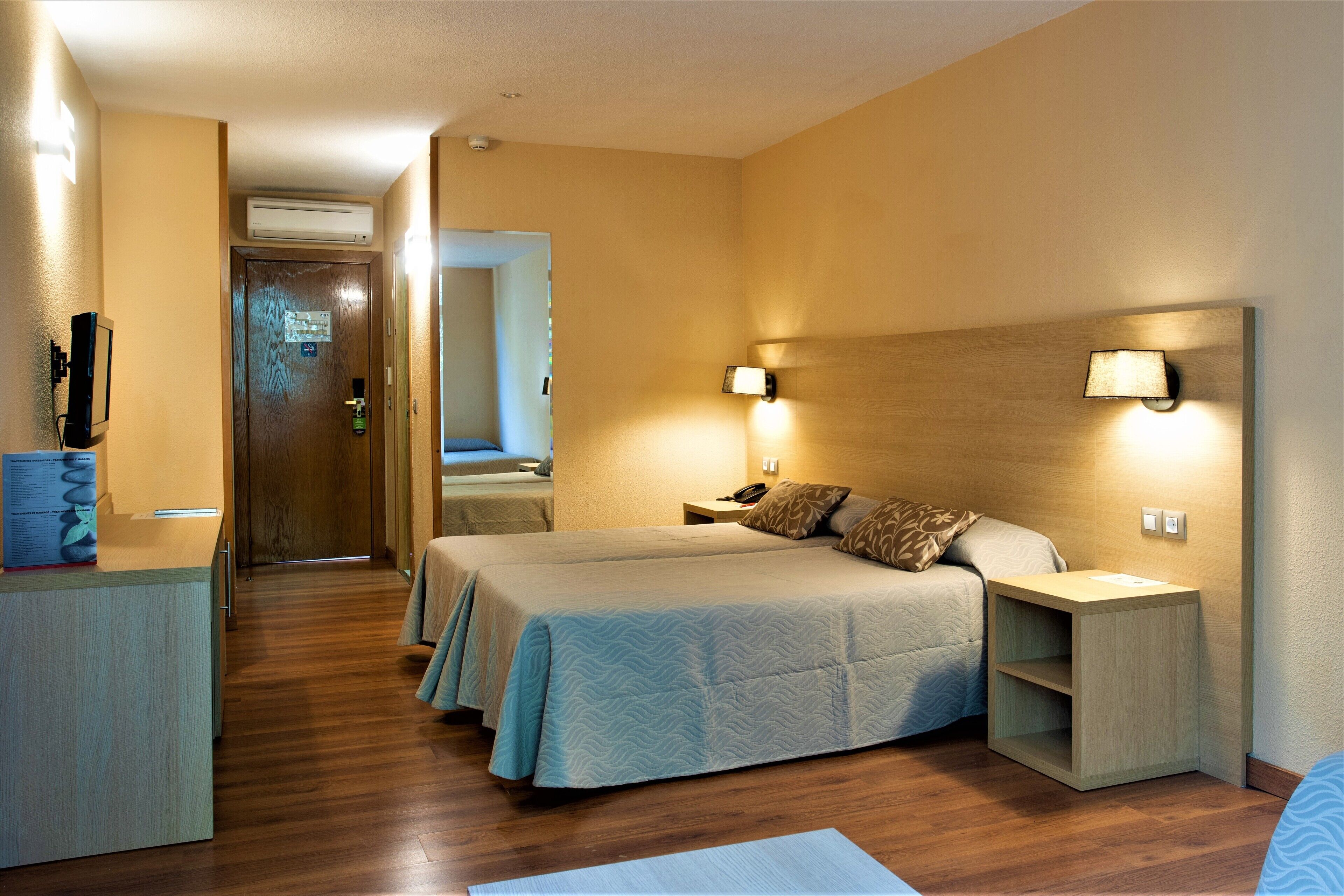 Habitación de hotel con dos camas, un escritorio y una mesita de noche.