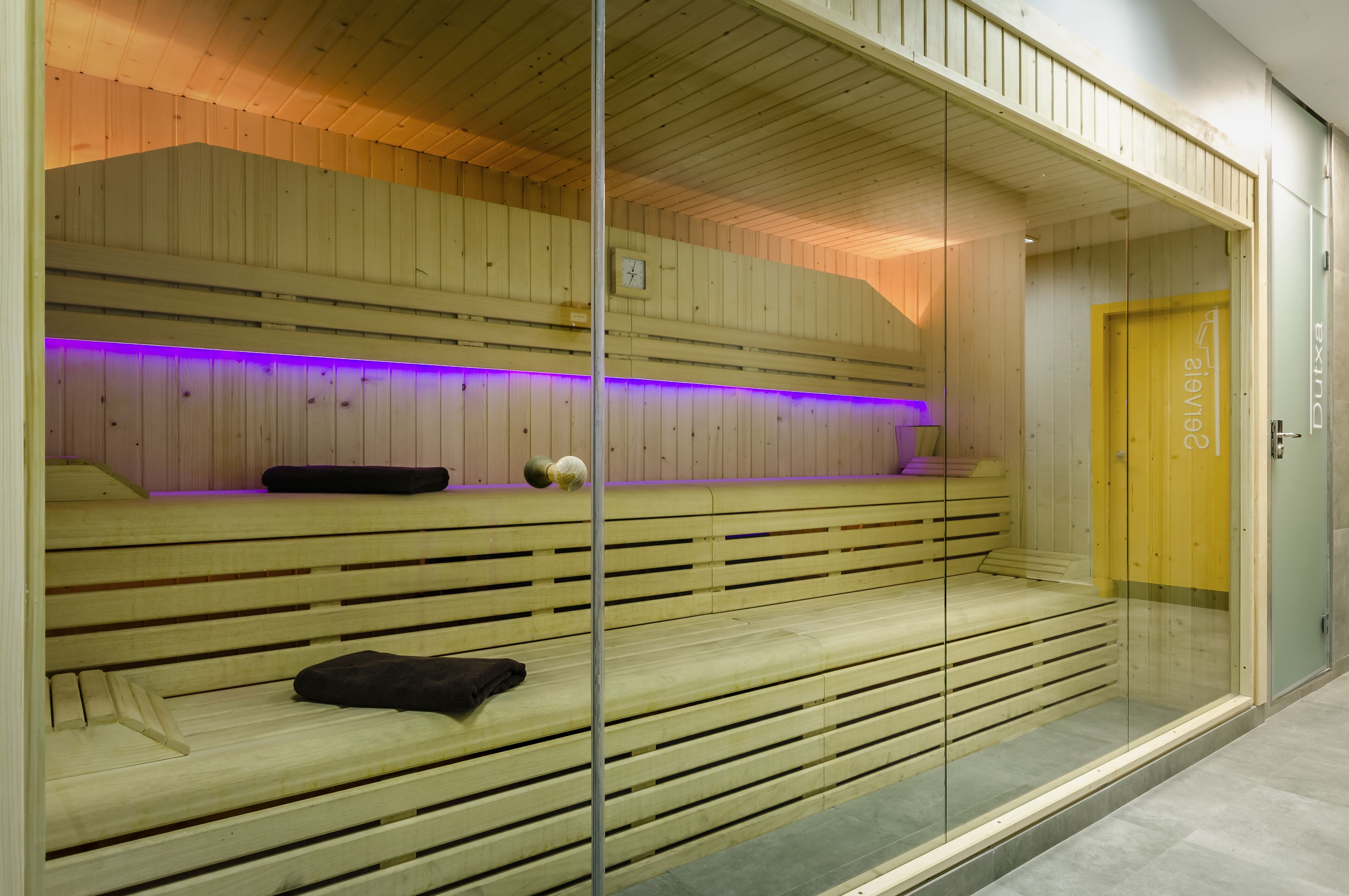 A sauna with wooden benches and a glass partition.