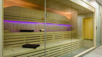 Una sauna con bancos de madera y un separador de vidrio.