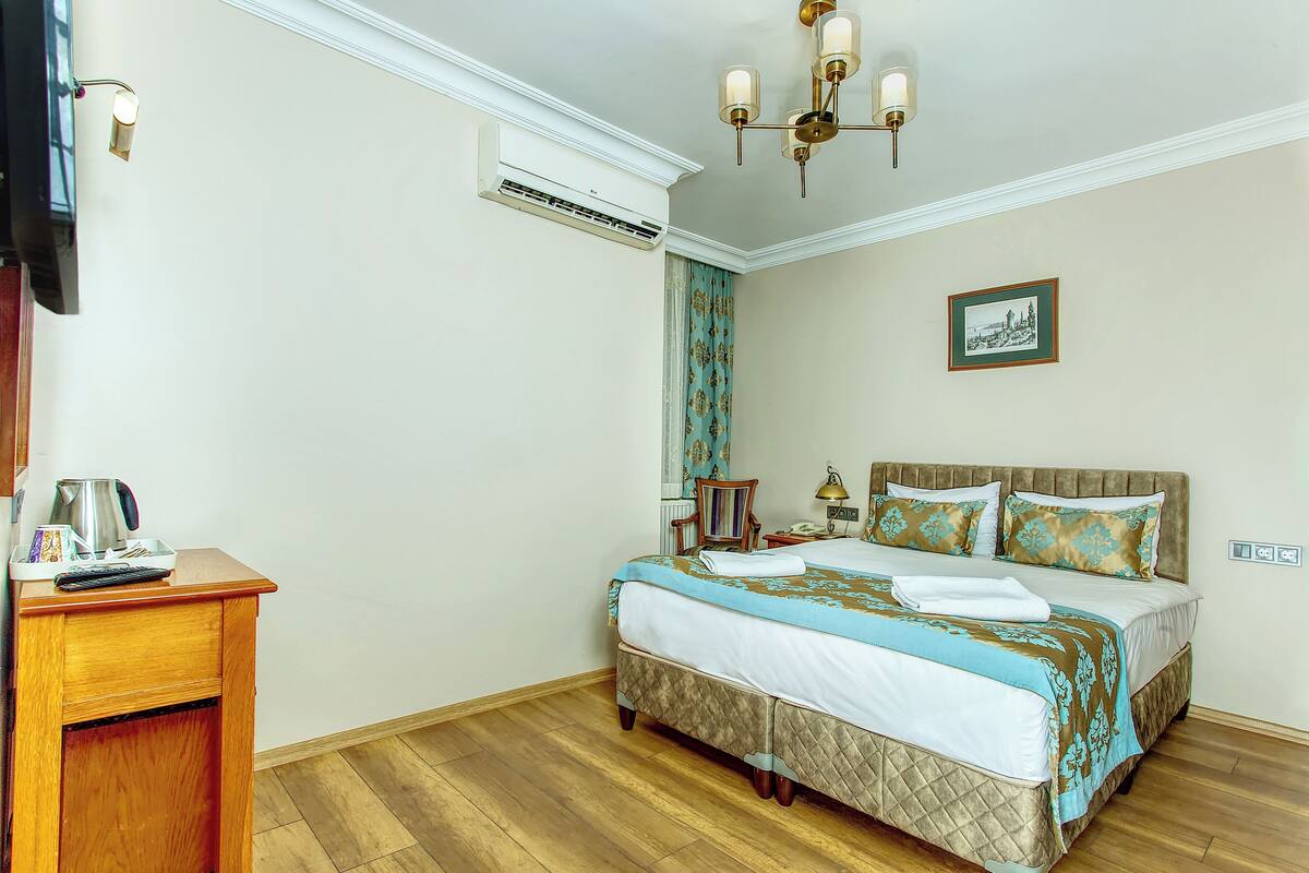 A neatly arranged hotel room with a bed, bedside table, and a picture on the wall.