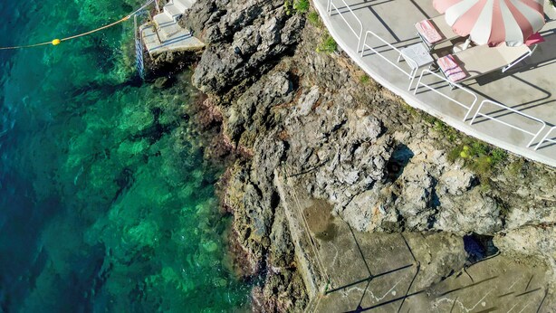 A coastal resort with a series of steps leading down to the beach, featuring sun loungers and umbrellas.