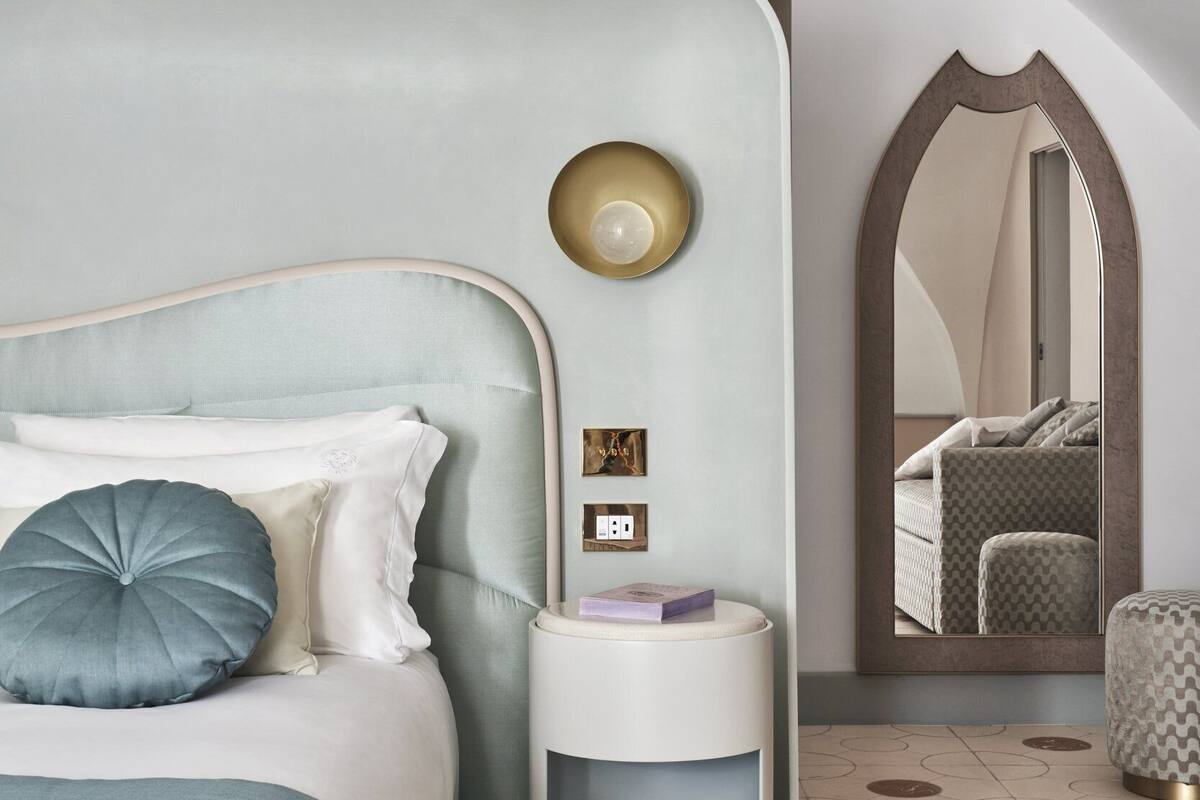 Un dormitorio con cama, mesita de noche y espejo.