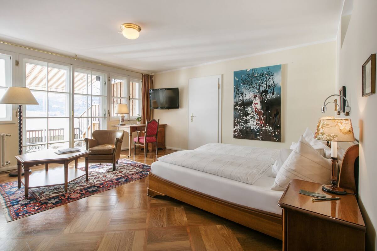 Une chambre d’hôtel avec un lit, un bureau et une chaise, une télévision et une grande fenêtre.