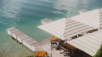 Ein Resort mit Bungalows über dem Wasser, klarem türkisblauem Wasser und einer Holzterrasse.
