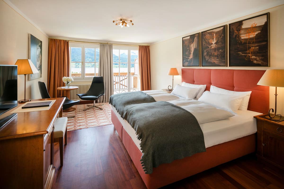 Une chambre d’hôtel avec un grand lit, un bureau, une chaise et une vue sur l’extérieur.