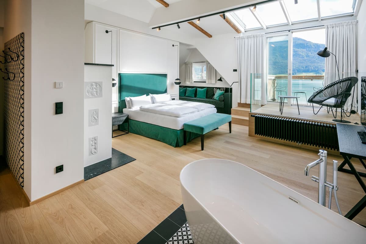 Une chambre moderne dotée d’un grand lit, d’un coin salon avec vue et d’une salle de bain séparée.