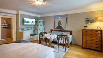 A hotel room with a bed, a dining table with chairs, a dresser, and a TV mounted on the wall.