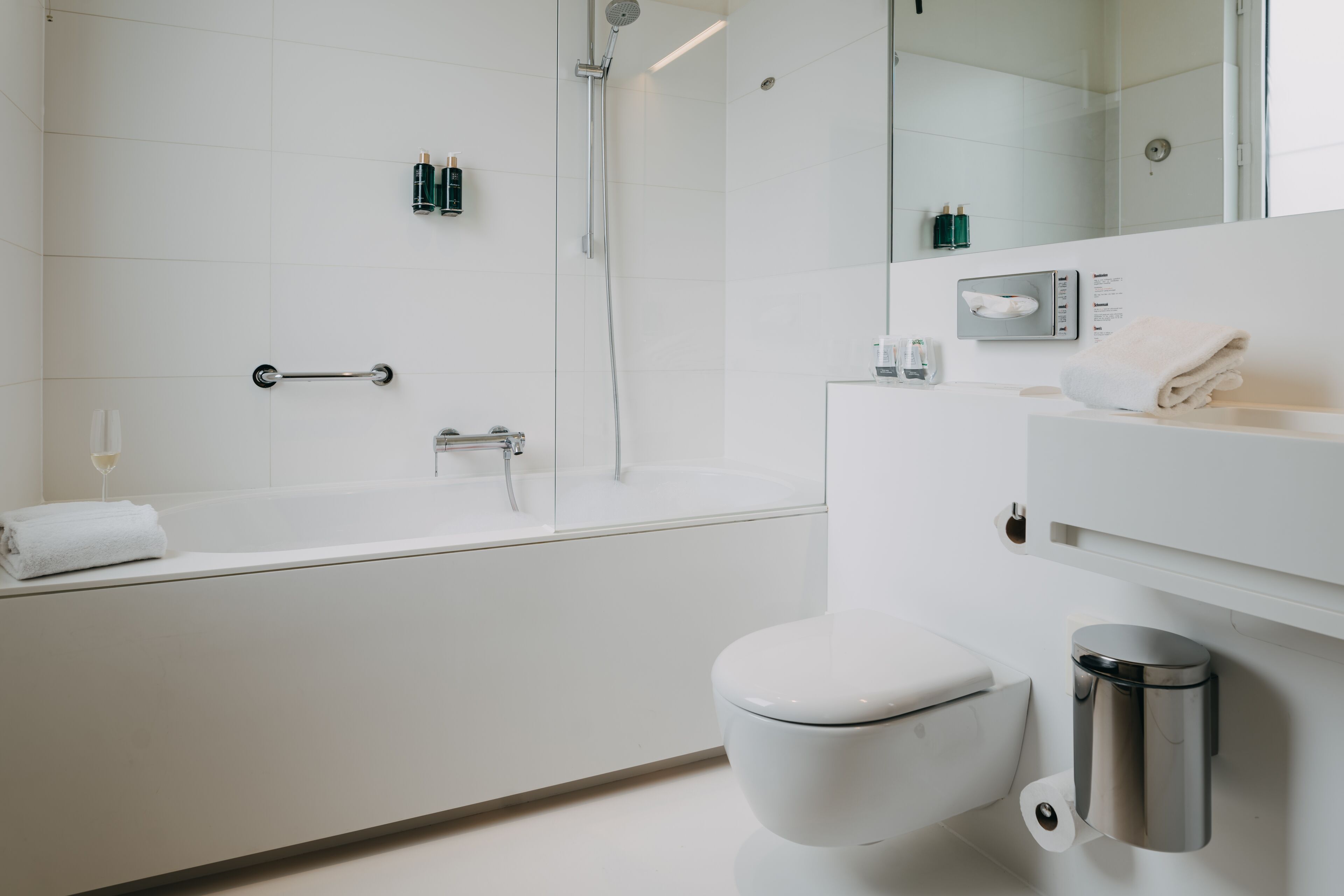 Une salle de bain moderne équipée d’une baignoire, de toilettes et d’un sèche-mains.