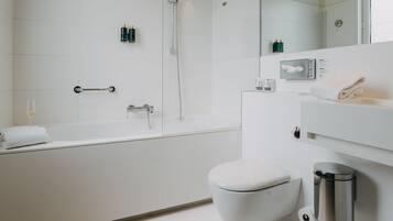 Une salle de bain moderne équipée d’une baignoire, de toilettes et d’un sèche-mains.