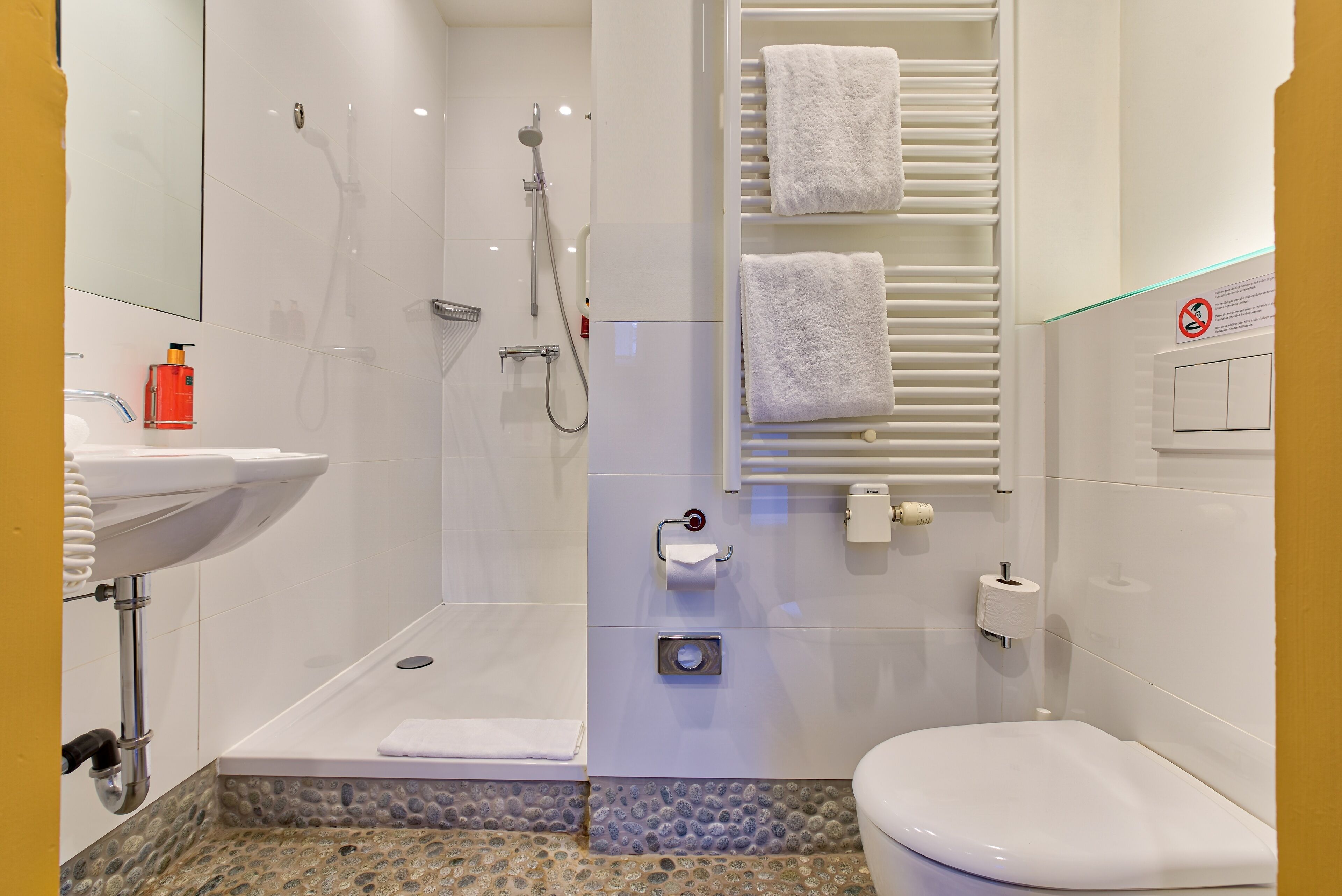 A modern bathroom with a shower, toilet, and sink.
