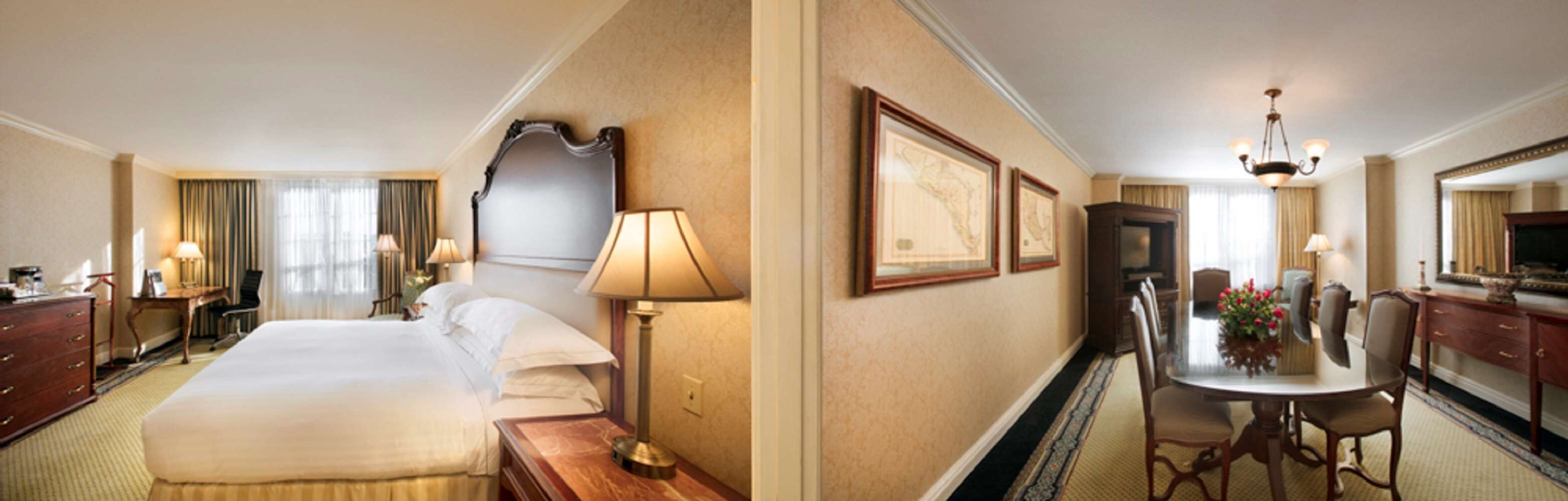 A hotel room with a large bed, bedside tables, a desk, and a dining area with chairs and a table.