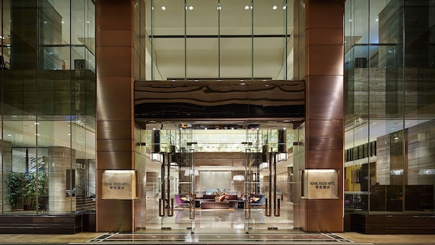 A hotel lobby with a central seating area, glass walls, and a modern design.