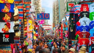 A crowded street market with various stalls and signs, including a prominent $10 sign.