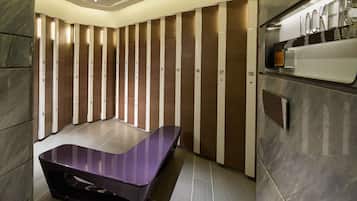A modern bathroom with individual lockers, a vanity with a mirror, and a purple bench.