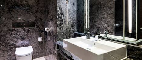 Un baño moderno con un lavamanos grande, espejo y retrete.