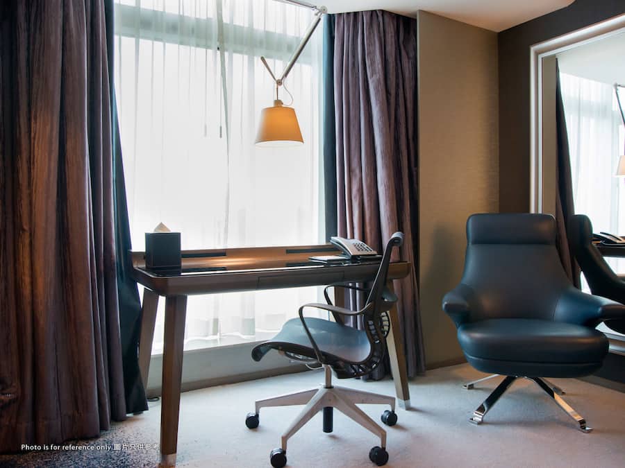 Une chambre d’hôtel équipée d’un bureau, d’un fauteuil de bureau et d’un téléphone.