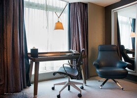 A hotel room with a desk, office chair, and a telephone.