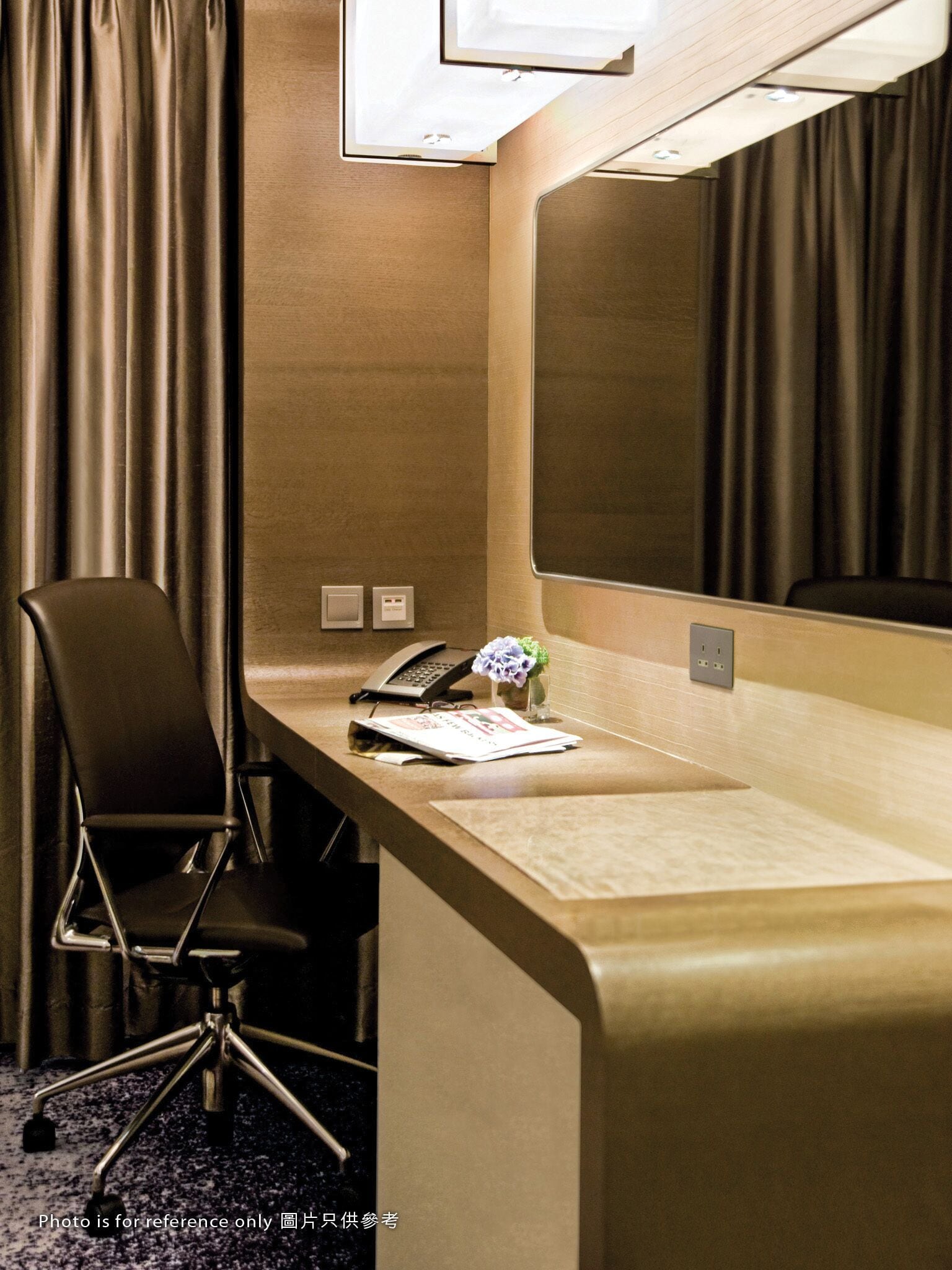 A hotel room with a desk, chair, telephone, and a mirror.