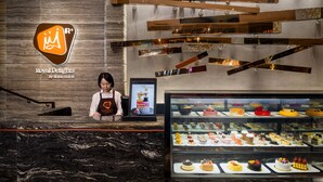 A dessert display case in a hotel lobby with a marble floor and a wall-mounted sign.