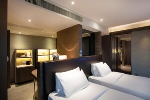A hotel room with two beds, a desk with a lamp, and a mirror.