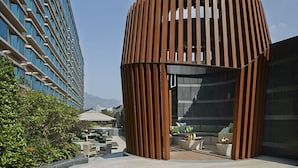 A modern building with a curved wooden facade and a rooftop patio area with outdoor seating and a fire pit.