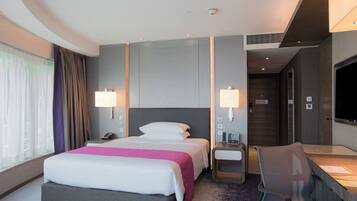 A modern hotel room with a large bed, bedside tables, a desk, and a TV.