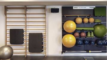 Een sportschool met fitnessapparatuur, waaronder een optrekstang, medicijnballen en een wandrek.