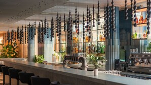 A bar area with a long counter, multiple stools, and hanging spherical decorations. - Swissôtel Kursaal Bern (Bern)