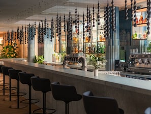 A bar area with a long counter, multiple stools, and hanging spherical decorations. - Swissôtel Kursaal Bern (Bern)