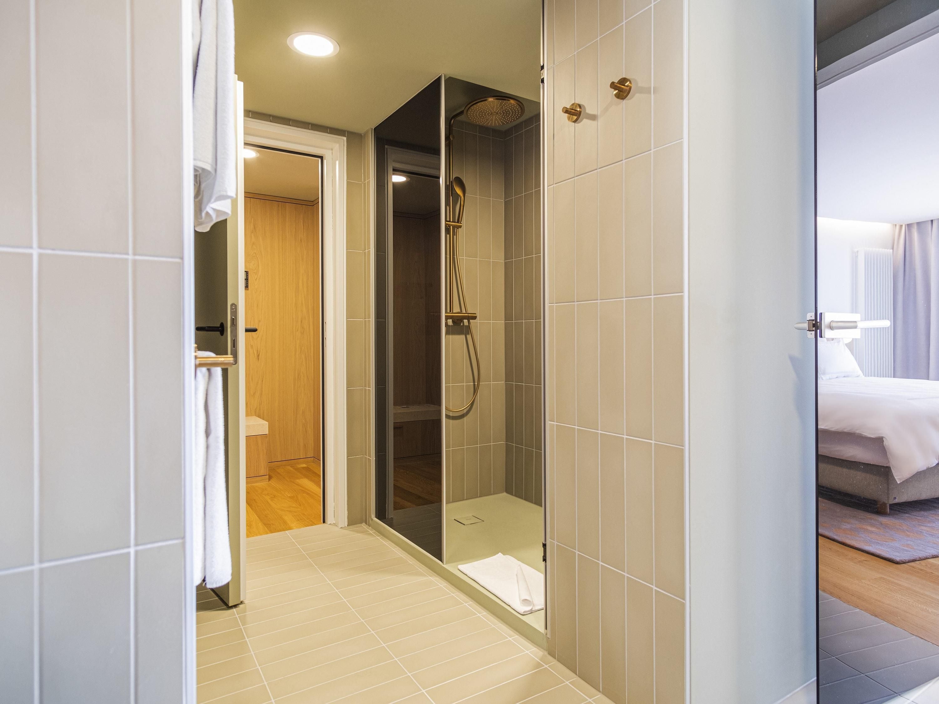 A modern bathroom with a glass-enclosed shower, a wooden door, and a visible towel rack.