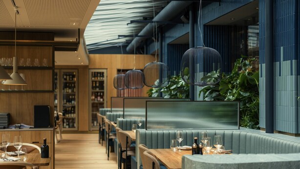 A modern restaurant with wooden flooring, blue upholstered seating, and hanging pendant lights. - Swissôtel Kursaal Bern (Bern)