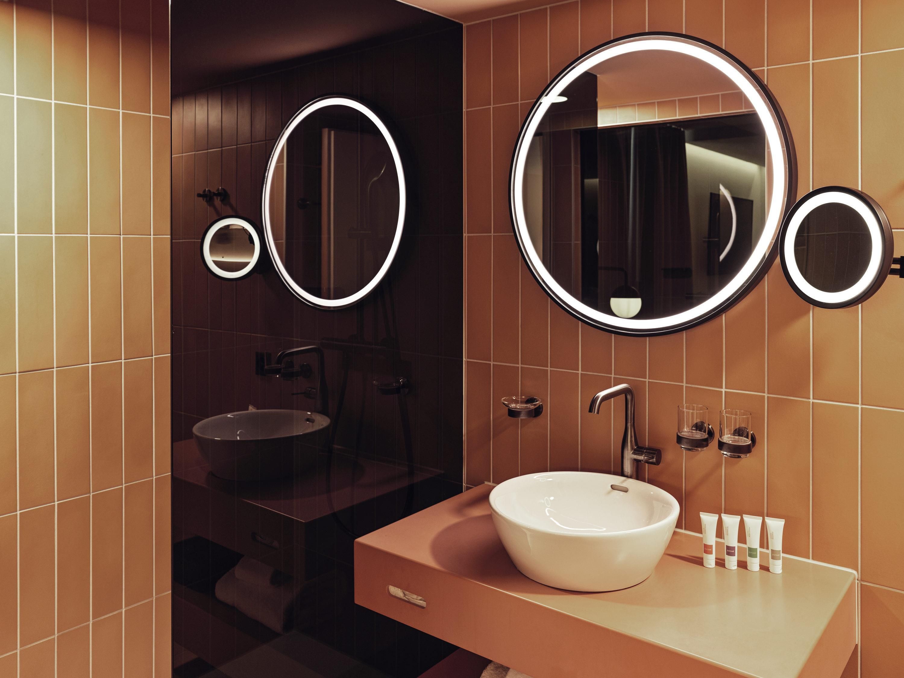A modern bathroom with a large round mirror, a sink, and a vanity.