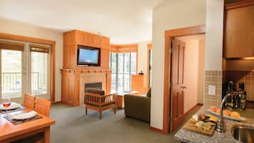 A modern kitchen with a built-in TV, wooden cabinets, a dining area with a table and chairs, and a cozy seating area with a fireplace.