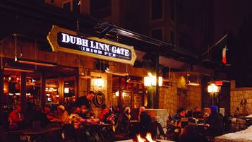 An outdoor seating area of a pub with a stone fireplace and a sign reading "DUB H LNN GATE IRISH PUB".