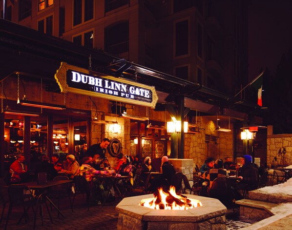 An outdoor seating area of a pub with a stone fireplace and a sign reading "DUB H LNN GATE IRISH PUB".