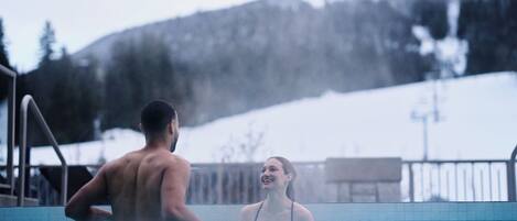 Un hombre y una mujer en una piscina con montañas al fondo.