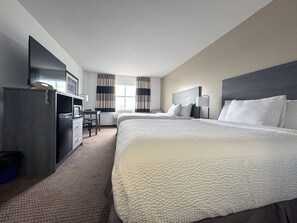 Een hotelkamer met twee bedden, een bureau, een stoel, een televisie en een raam met gordijnen.