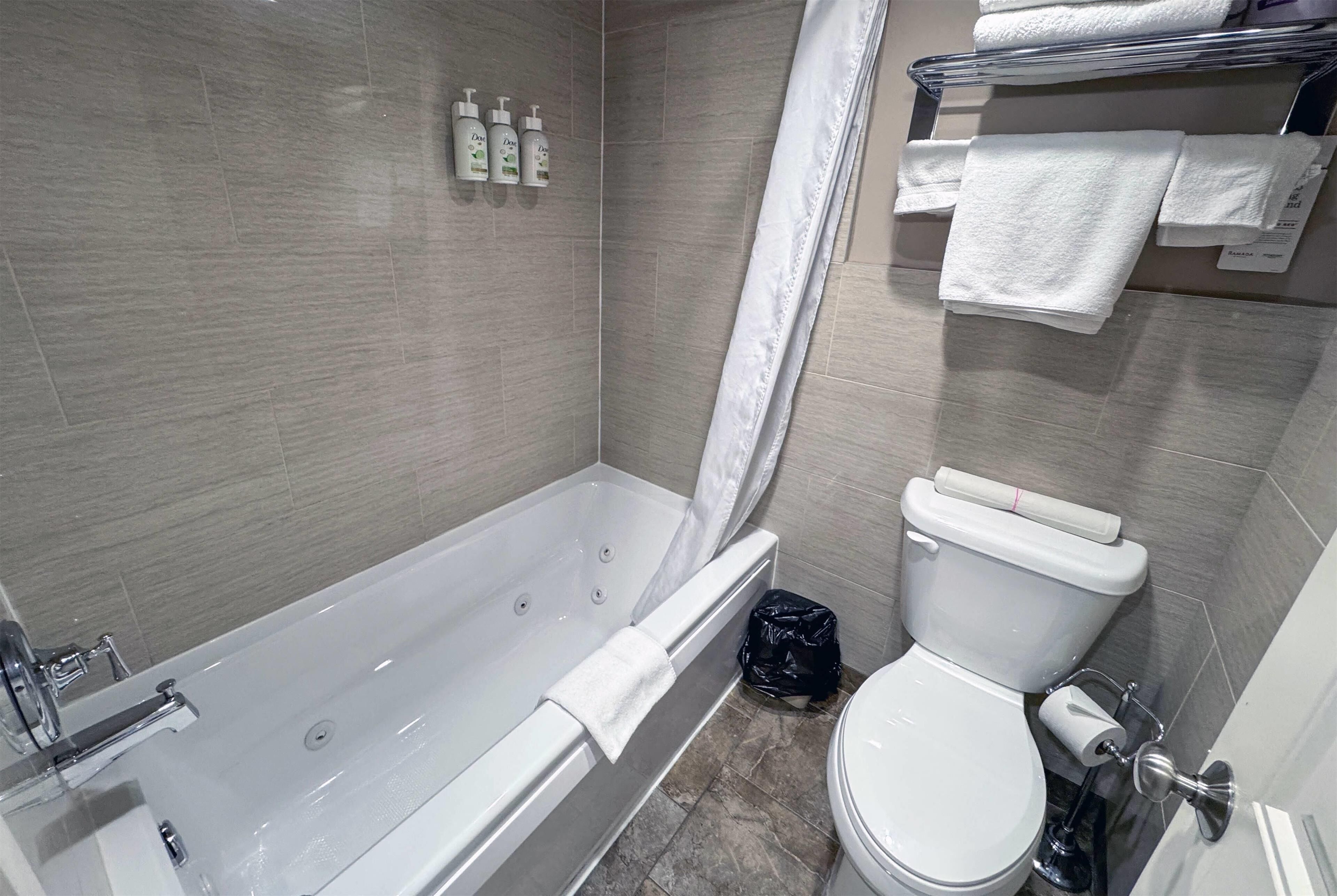 A modern bathroom with a bathtub, toilet, and shower curtain.