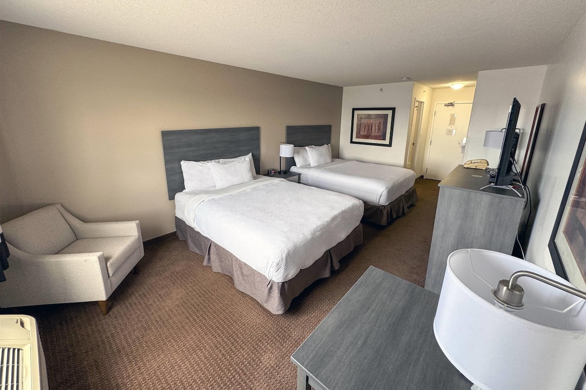 Une chambre d’hôtel avec deux lits, une chaise, un bureau et une salle de bain.