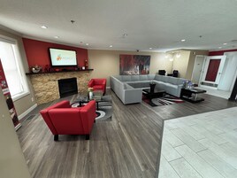 Una sala de estar moderna con chimenea, sofás rojos y grises, un sofá grande tipo seccional y un televisor de pantalla plana montado en la pared.